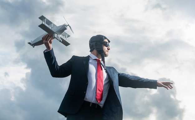 Uomo d'affari in tuta e cappello da pilota lancia il concetto di giocattolo aereo di progresso