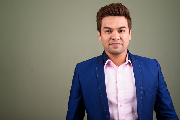Uomo d'affari indiano che indossa tuta contro sfondo colorato