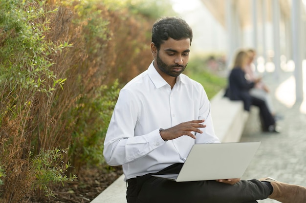 Uomo d'affari indiano che utilizza un computer portatile con videochiamata, comunicazione online sul posto di lavoro