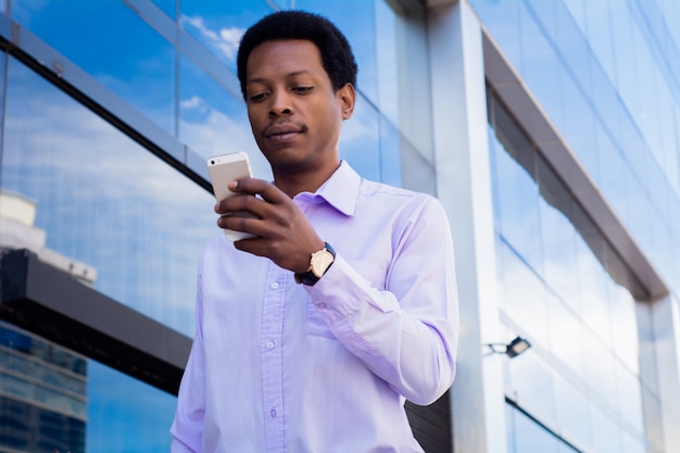 Uomo d&#39;affari latino che utilizza telefono cellulare nella città.