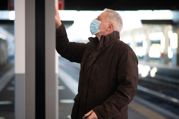 Uomo d'affari mascherato in attesa del concetto di mobilità del treno covid e del coronavirus