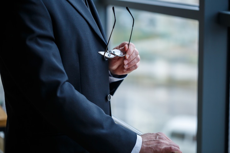 Foto uomo d'affari maschio adulto, insegnante, mentore guarda fuori dalla grande finestra del suo ufficio. lavoro in ufficio. sviluppo di un nuovo progetto imprenditoriale