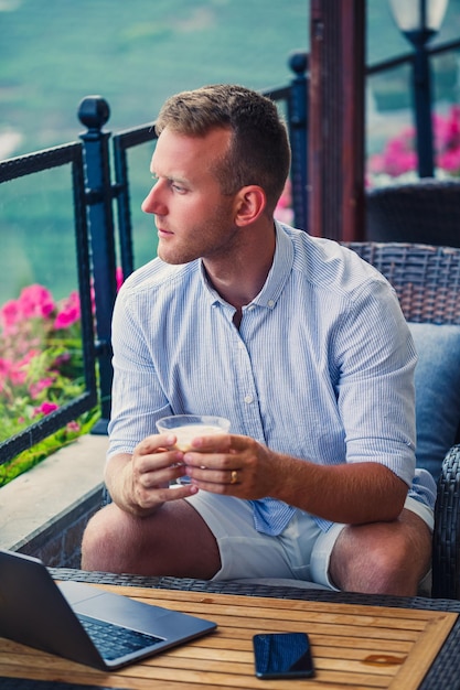 Uomo d'affari maschio che lavora su laptop al bar sul tetto con bella vista panoramica Guy blogger beve caffè e lavora su un computer durante il viaggio