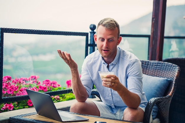 Uomo d'affari maschio che lavora su laptop al bar sul tetto con bella vista panoramica Guy blogger beve caffè e lavora su un computer durante il viaggio