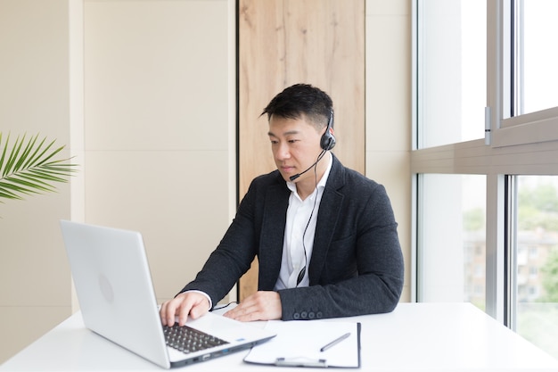 Uomo d'affari maschio conduce formazione online utilizzando un auricolare e un laptop