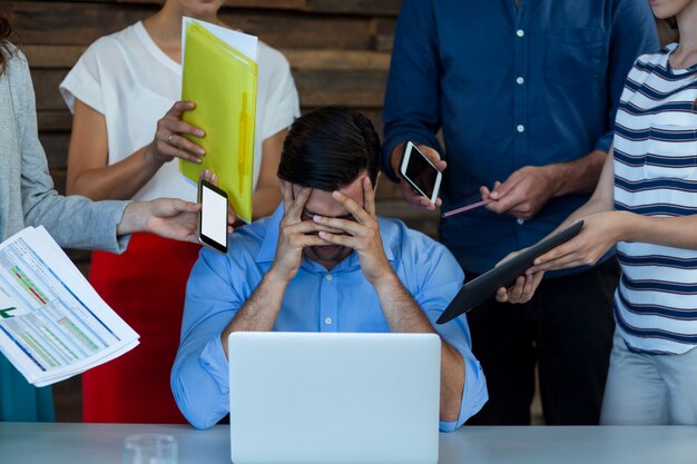 Uomo d'affari maschio frustrato che si siede con il computer portatile allo scrittorio