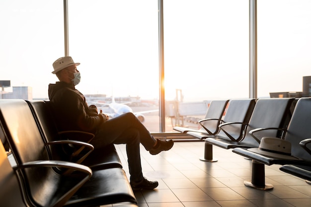 Uomo d'affari maturo all'aeroporto nella sala d'attesa Ritratto di uomo latino seduto con una maschera