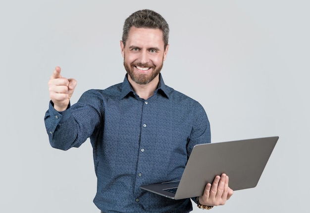 Uomo d'affari maturo bello di successo con la barba che lavora online sul successo di affari del dito puntato del computer portatile