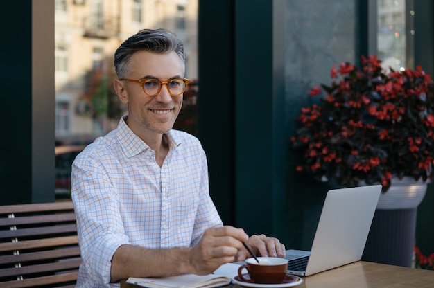 Uomo d'affari maturo che beve caffè nella caffetteria. Concetto di pausa caffè