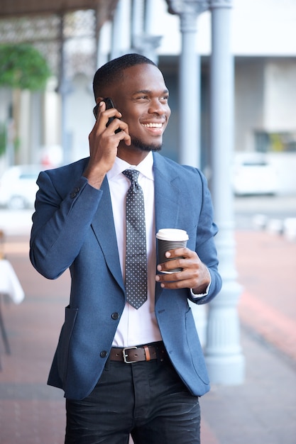 Uomo d&#39;affari moderno che cammina e che parla sul telefono cellulare