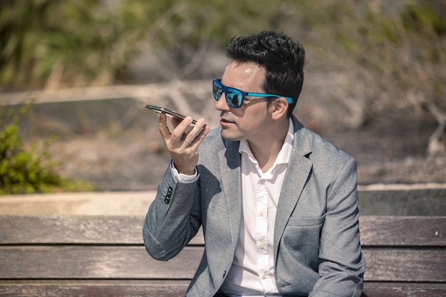 Uomo d'affari moderno che registra messaggio vocale sullo smartphone