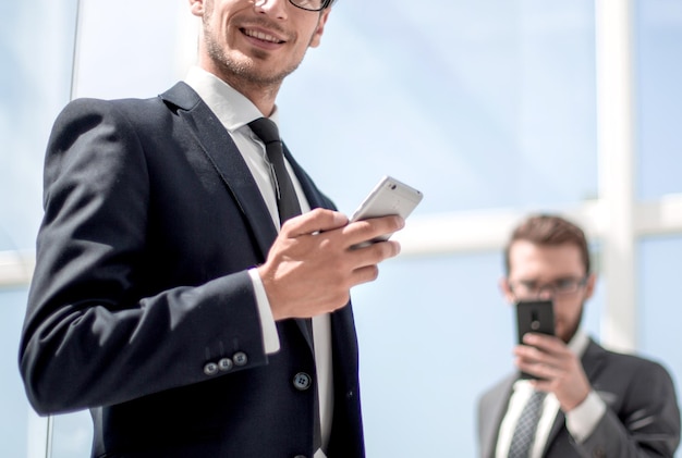 Uomo d'affari moderno con uno smartphone sull'ufficio in background