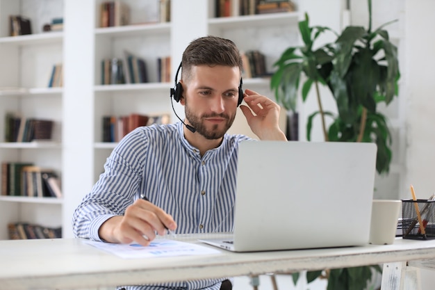 Uomo d'affari moderno premuroso che lavora utilizzando il computer portatile mentre è seduto in ufficio.