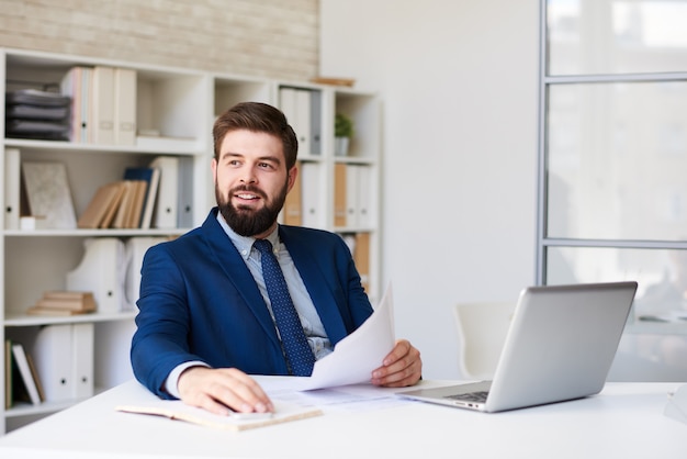 Uomo d'affari moderno sicuro in ufficio con un computer portatile