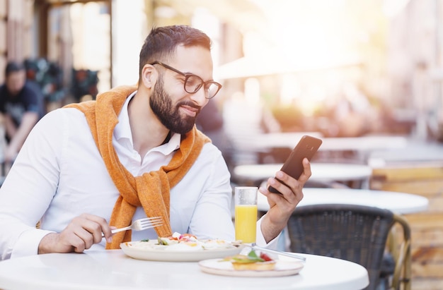 Uomo d'affari multiculturale barbuto in camicia bianca con conversazione telefonica al bar