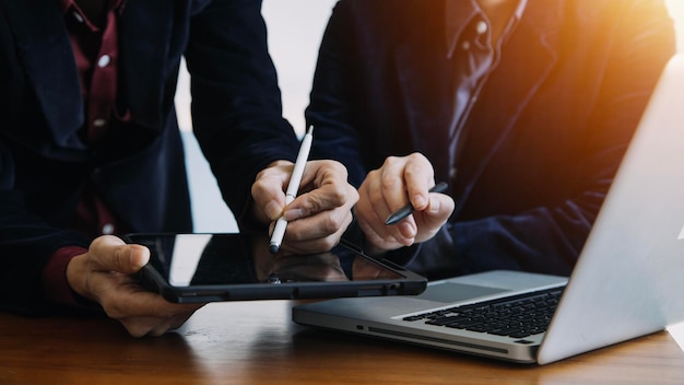 Uomo d'affari multitasking che lavora in ufficio Sta usando il touchpad mentre legge un'e-mail sul laptop e prende appunti sulla carta