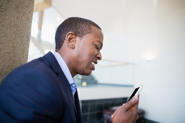 Uomo d'affari preoccupato che esamina telefono cellulare