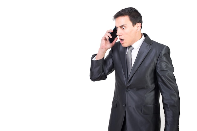 Uomo d'affari sbalordito in giacca e cravatta che parla sullo smartphone