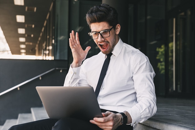 Uomo d'affari scioccato vicino al centro business utilizzando il computer portatile.