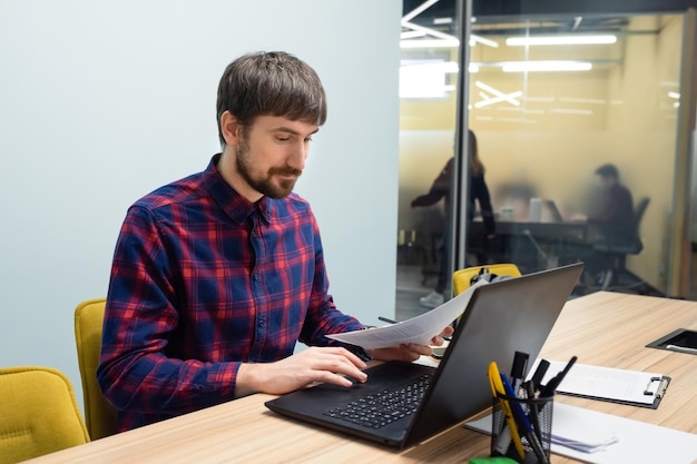 Uomo d'affari seduto a un tavolo da ufficio che lavora su un computer portatile