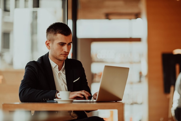 uomo d'affari seduto alla caffetteria con un laptop e uno smartphone. Uomo d'affari che invia messaggi sullo smartphone mentre è seduto in un ristorante pub. Uomo d'affari che lavora e controlla la posta elettronica sul computer.