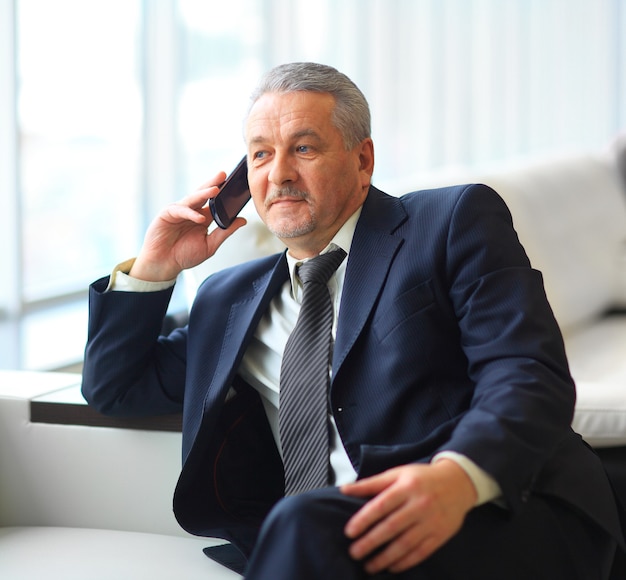 uomo d'affari seduto e parlando al telefono