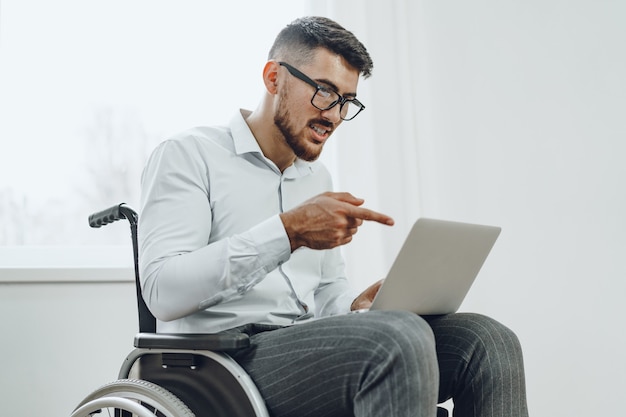 Uomo d'affari seduto in sedia a rotelle e utilizzando laptop