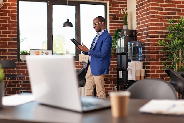 Uomo d'affari seduto in ufficio e utilizza la tavoletta digitale per lavorare sulla strategia di marketing. Impiegato dell'azienda che lavora su internet con gadget per pianificare progetti finanziari, idee di brainstorming.