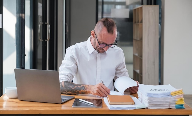 Uomo d'affari serio che utilizza un computer portatile seduto al tavolo in un ufficio domestico guardando la carta che comunica online scrivendo e-mail lavorando a distanza sul computer