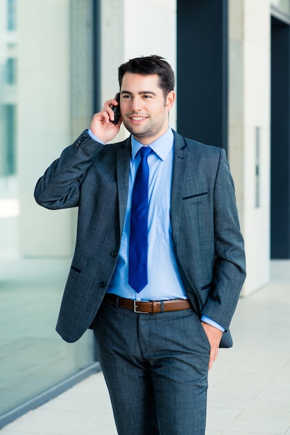 Uomo d&#39;affari sicuro all&#39;aperto usando il telefono