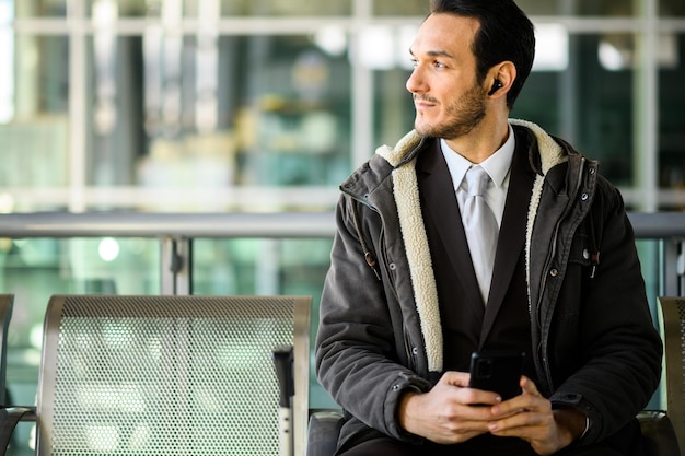 Uomo d'affari sicuro con uno smartphone in attesa alla stazione