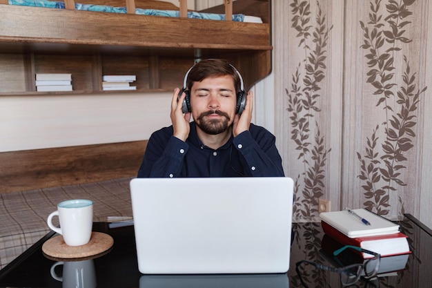 Uomo d'affari soddisfatto che indossa le cuffie per godersi la musica a casa