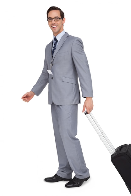 Uomo d&#39;affari sorridente che cammina con la sua valigia