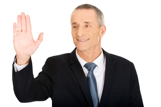Uomo d'affari sorridente che fa un gesto mentre si trova sullo sfondo bianco
