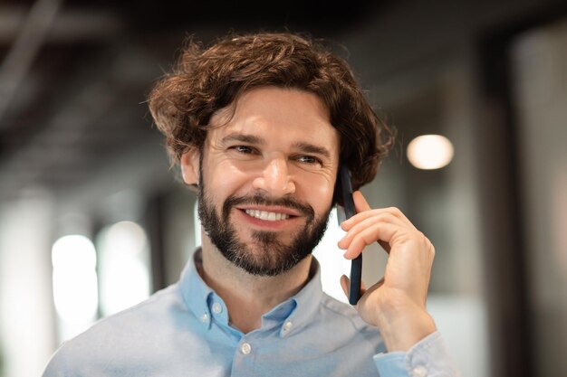 Uomo d'affari sorridente che lavora e parla al telefono in ufficio