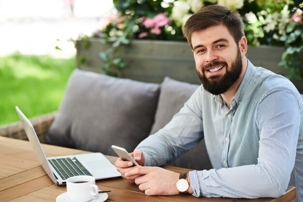 Uomo d'affari sorridente che lavora in caffè