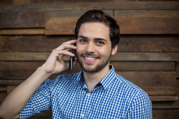 Uomo d'affari sorridente che parla sul telefono cellulare in ufficio