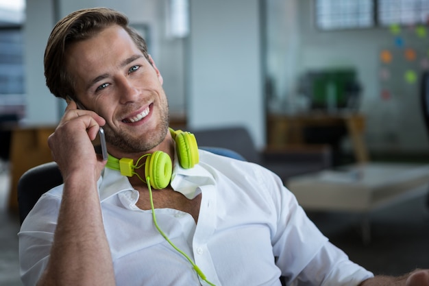 Uomo d'affari sorridente che parla sul telefono cellulare