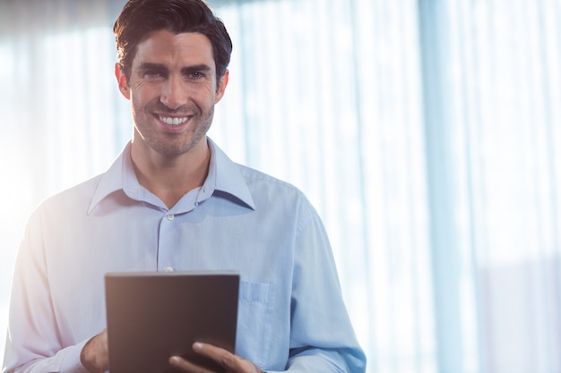 Uomo d'affari sorridente che per mezzo di un computer della compressa