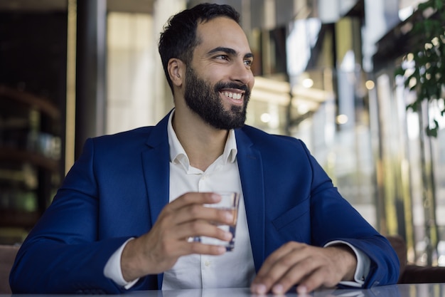 Uomo d'affari sorridente che tiene un bicchiere d'acqua