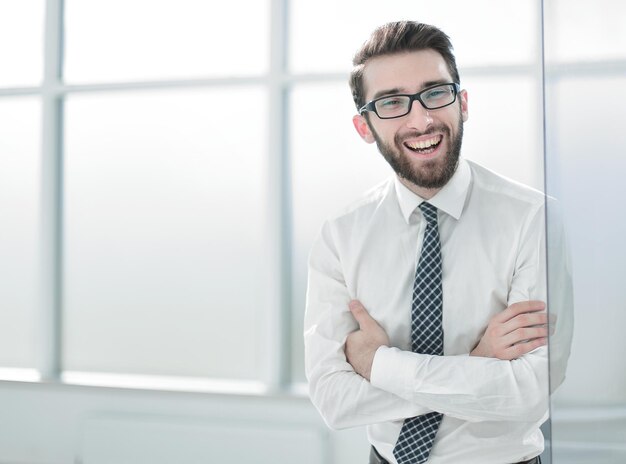 Uomo d'affari sorridente in piedi vicino alla finestra dell'ufficio