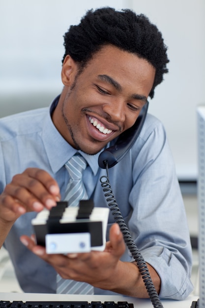 Uomo d&#39;affari sorridente sul telefono che esamina il titolare della carta