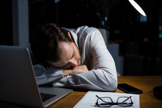 Uomo d'affari stanco che dorme sullo scrittorio