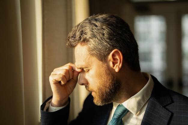 Uomo d'affari stressato che ha mal di testa in ufficio L'uomo d'affari stanco sta facendo gli straordinari e ha