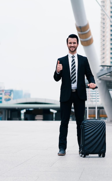 Uomo d'affari trasportare bagagli Imprenditore bello in piedi all'aperto Concetto di viaggio d'affari turismo comunicazione e vestito formalmente