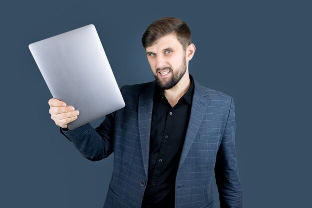 Uomo d'affari un uomo con la barba in un abito blu che tiene un laptop in una mano