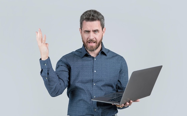 Uomo d'affari uomo maturo bello infelice con la barba che lavora online sul capo del laptop