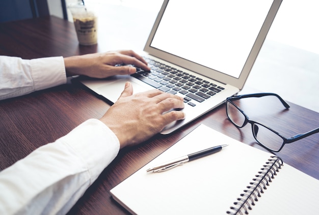 Uomo d'affari utilizzando il computer portatile con schermo vuoto nel negozio di caffè