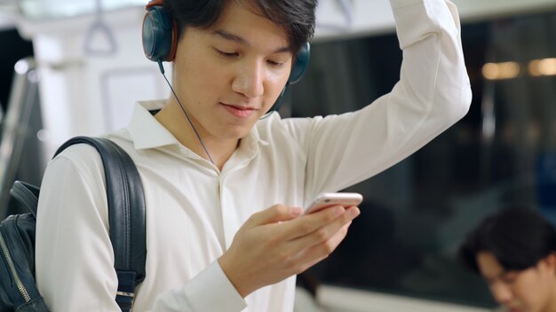 Uomo d'affari utilizzando il telefono cellulare sul treno pubblico. Concetto di pendolarismo urbano stile di vita della città.