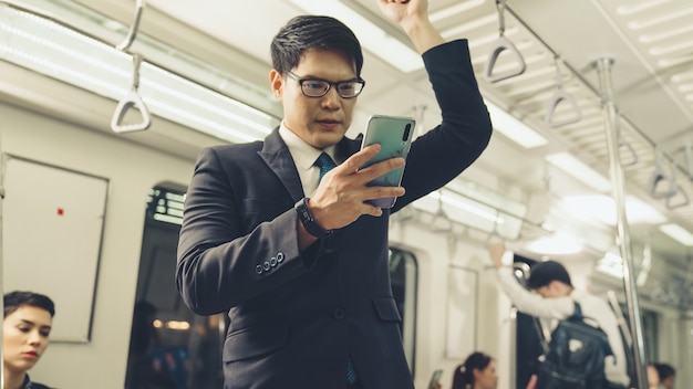 Uomo d'affari utilizzando il telefono cellulare sul treno pubblico